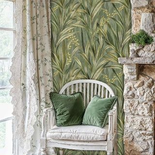 Sage green palm frond wallpaper in cozy reading nook with white vintage chair and stone fireplace