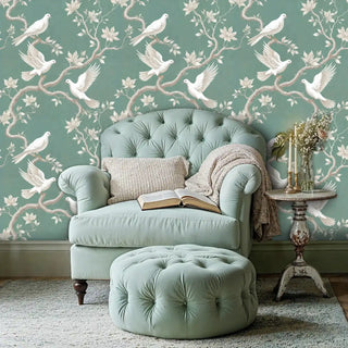 Sage green wallpaper with white doves and magnolia blooms, featured in reading nook with tufted armchair