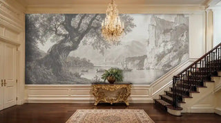 Scenic lakeside wall mural with ancient tree and sailing vessels displayed in grand entryway with curved staircase