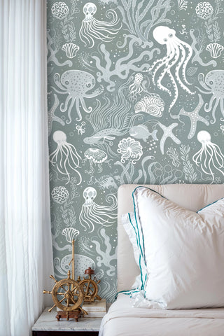 Sea life wallpaper with jellyfish and kelp patterns, displayed in bedroom with brass ship wheel decor