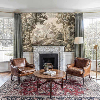 Sepia pastoral wallpaper depicting horses in forest clearing, installed in living room with marble fireplace
