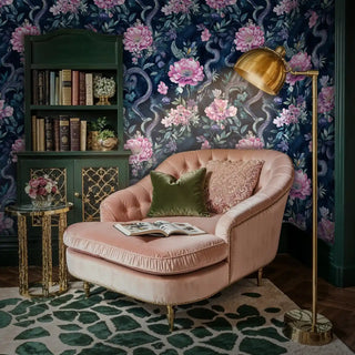 Serpentine floral wallpaper with pink peonies and navy background, shown in reading nook with leather armchair