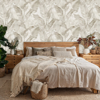Soft tropical leaves wallpaper in muted colors, featured in serene bedroom with natural wood furniture and plants