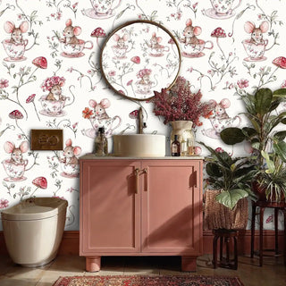 Storybook mice wallpaper in pink and cream tones displayed in elegant powder room with round mirror and plants