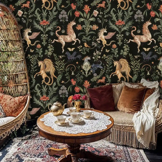 tapestry-style unicorn wallpaper with coral flowers and gold figures on black, shown in a boho sitting area with tea set on wooden table