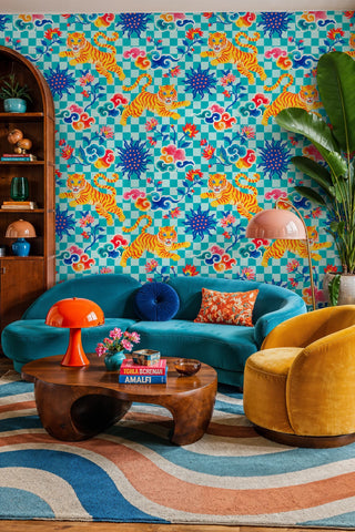 Teal checkered tiger wallpaper with swirling clouds and florals, in a living room with curved teal sofa