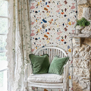 Terrazzo stone wallpaper with colorful fragments, displayed in charming nook with white wooden chair and stone wall