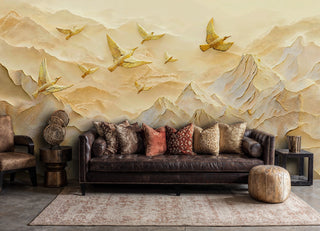 Textured golden bird and mountain wall mural, shown in a warm living room with leather sofa and pouffe