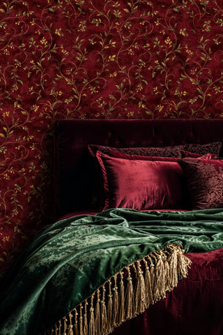 Traditional botanical wallpaper with golden scrollwork, shown in luxurious bedroom with emerald velvet bedding