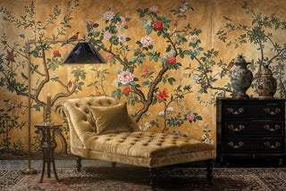 Traditional chinoiserie wall mural with golden birds and flowers shown in sophisticated reading nook with velvet chaise