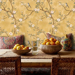 Traditional chinoiserie wallpaper featuring birds and blossoms, styled in bohemian dining area with woven furniture