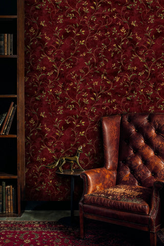 Traditional vine pattern wallpaper with golden leaves, showcased in classic study with ornate leather armchair
