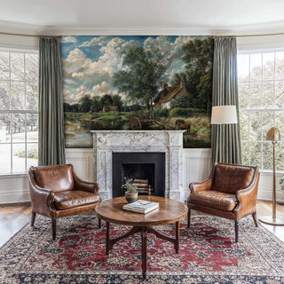 Tranquil countryside wall mural with water mill displayed in bright living room with marble fireplace and leather chairs