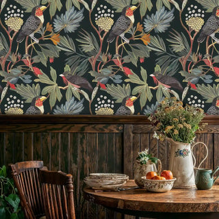 Tropical bird wall mural with toucans and palm patterns shown in rustic dining room with wooden table and vintage chair