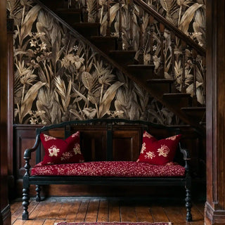 Tropical botanical wallpaper featuring golden lilies, shown in hallway with antique bench and red cushions