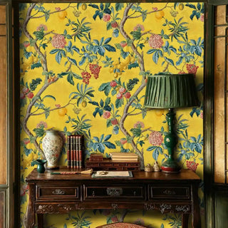 Tropical fruit wallpaper with branching vines and colorful flowers, in study with antique desk and green lamp