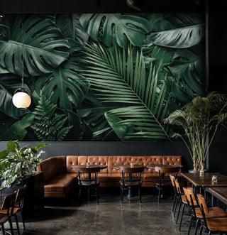 Tropical jungle wallpaper featuring large monstera leaves and palm fronds, displayed in modern cafe with leather banquette
