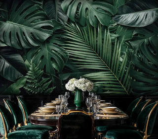 Tropical monstera wallpaper in deep greens with fern accents, shown in formal dining room with crystal chandelier