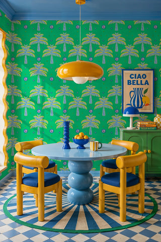 Tropical palm wallpaper in green with folk florals shown in a vibrant dining room with bubble table