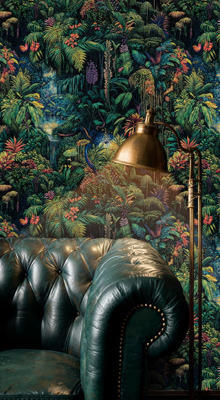 Tropical rainforest wallpaper with colorful foliage on dark background, in a study with leather Chesterfield sofa