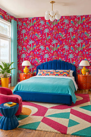 Tropical toucan wallpaper with palms and wildflowers on pink, in a bold bedroom with blue velvet bed