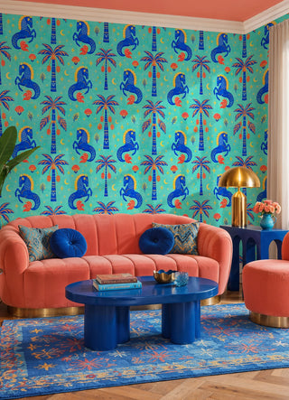 Turquoise horse and palm wallpaper with red florals and gold moons in a living room with coral sofa and blue table