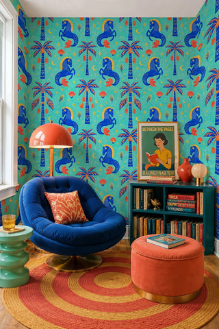 Turquoise wallpaper with blue horses and red motifs in a reading nook with swivel chair and bookshelf