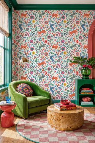 Vibrant folk art wallpaper with leaping leopards and snakes among flowers, in a colorful nook with green armchair