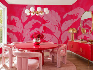 Vibrant red tropical leaf wall mural with pink foliage in a dining room with red round table and globe chandelier