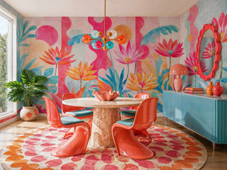 Vibrant tropical floral wall mural with pink blooms and teal leaves in a colorful dining room with coral chairs