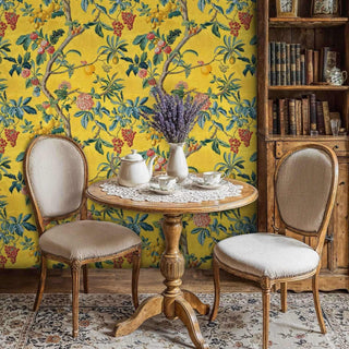 Vintage botanical wallpaper showing fruit trees and coral blooms, in cozy reading nook with wooden chairs