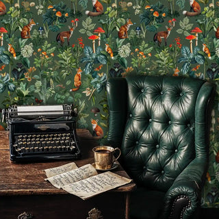 Vintage woodland wallpaper with foxes and mushrooms, shown in a dark study behind a vintage typewriter and a green leather chair.
