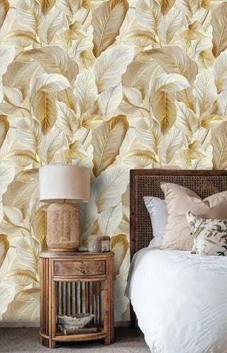 Warm tropical leaf wallpaper in honey tones, styled in cozy bedroom with rattan nightstand