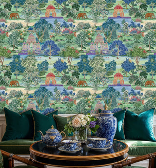 Watercolor Indian garden wallpaper with pavilions and lush trees, in an elegant sitting room with blue and white porcelain tea set