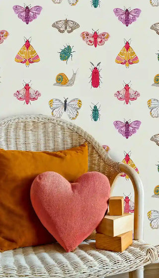 Whimsical insect wallpaper featuring colorful butterflies, beetles and snails in a cozy reading space with wicker chair