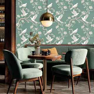 White dove wallpaper with magnolia branches in sage green, shown in elegant dining room with brass pendant
