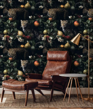 Wild leopard botanical wallpaper with jungle cats and foliage, displayed in modern living room with leather chair