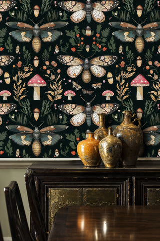 Woodland moth wallpaper with pink mushrooms and green foliage on dark ground, in a dining room with brass vases