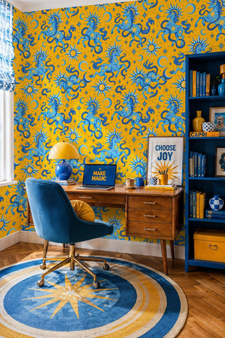 Yellow wallpaper with blue celestial horses and sunbursts, in a home office with mid-century wood desk
